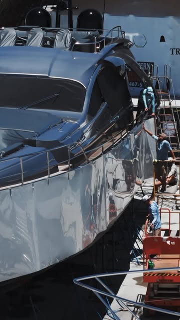 Team detailing the topsides of a large motor yacht on stands